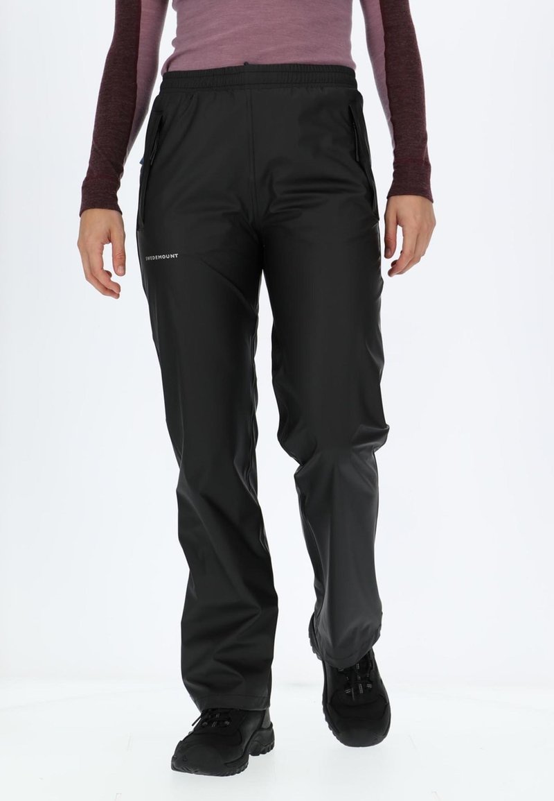 Pantaloni impermeabili neri con vita elastica, due tasche laterali con zip e una superficie liscia e lucida. Presentano il logo sulla coscia sinistra.