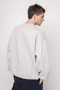 Felpa grigia con spalle scese, polsini a costine e orlo elastico. Realizzata in tessuto morbido, presenta una vestibilità rilassata e un design minimal.