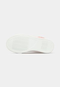 Λευκή λαστιχένια σόλα ροζ αθλητικού παπουτσιού, εμφανιζόμενη από κάτω με υφή λαβής και επίπεδη φτέρνα.