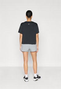 Μαύρο κοντομάνικο t-shirt Nike και ανοιχτόγκρι σορτς, με καθαρή κοπή, μαλακό ύφασμα και μικρό λογότυπο στην πλάτη. Μαύρα αθλητικά παπούτσια.