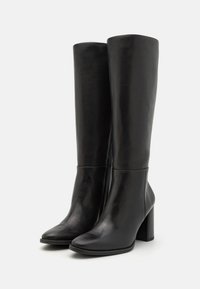 Botas de cuero negro hasta la rodilla con punta cuadrada, tacón alto grueso y cremallera lateral. Textura suave con un diseño minimalista.