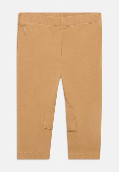 Ανοιχτό καφέ κολάν από απαλό βαμβάκι με εφαρμοστή σχεδίαση. Διαθέτει ραμμένη μέση και υφασμένη επιφάνεια στο γόνατο σε κάθε πόδι.