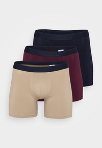 Drei Paar Herren-Boxershorts in Beige, Burgunderrot und Marineblau. Jede hat einen weichen Bund mit dem Markennamen und ist aus glattem Stoff gefertigt.
