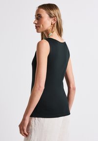 Musta hihaton paita, jossa on pyöreä pääntie ja tiukka muotoilu, valmistettu sileästä kankaasta. Takana on yksinkertainen siluetti.