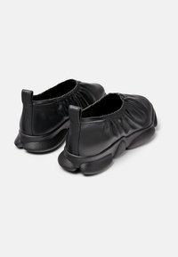 Czarne buty wsuwane wykonane z gładkiej skóry z marszczonymi detalami wokół kostki oraz teksturowanymi czarnymi gumowymi podeszwami dla lepszej przyczepności.