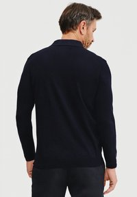 Granatowy sweter polo z długim rękawem o miękkiej fakturze, z ryflowanym dołem i kołnierzykiem, pokazany z tyłu.