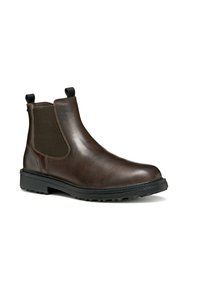 Botas Chelsea de cuero marrón con paneles laterales elásticos, puntera redonda, lengüetas en la parte trasera y suela de goma negra con tacos. Textura suave con detalles de costura.