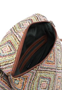 Sac tissé multicolore avec un motif géométrique, garniture en cuir brun et intérieur sombre doté d'une poche zippée.