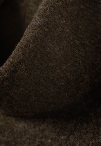 Pruun villa kangas lähivaates, millel on tekstuuriga pind, pehme ja udune välimus ning erinevad pruuni toonid. Märkimisväärne sügavus ja soojus.