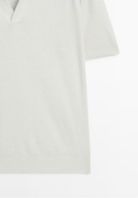 Polo à manches courtes en maille gris clair avec motif texturé, poignets côtelés et col en V.