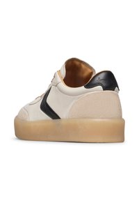 Sneaker bianca in pelle con accento nero, interno marrone chiaro e suola beige texturizzata. Forma arrotondata con chiusura con lacci e finitura liscia.
