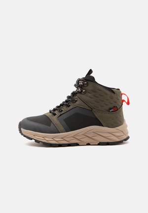 Chaussure de randonnée montante imperméable en vert olive et noir avec semelle beige et languette rouge, vue de côté sur fond blanc.