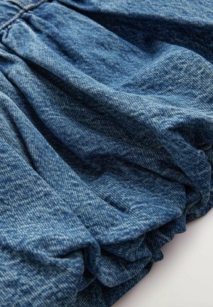 Tessuto denim di un blu intenso, caratterizzato da una texture arricciata che crea morbide pieghe. Superficie liscia con leggere variazioni di colore.