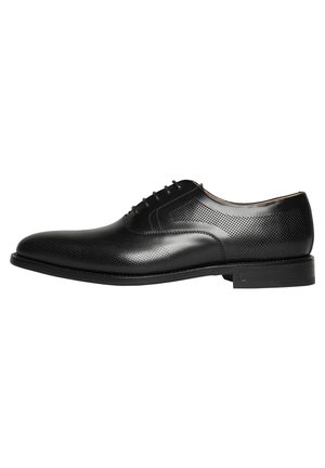Schwarze Lederleder Schuhe mit perforiertem Design, abgerundeter Zehenform, Schnürverschluss und einer flachen Gummisohle, mit subtilen tonalen Akzenten.