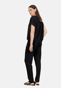 Schwarzes Sweatshirt- und Hosen-Set, aus weichem Stoff, lockerer Schnitt, Drop-Ärmel, elastischer Bund, kombiniert mit hellbraunen, durchbrochenen Ballerinas.