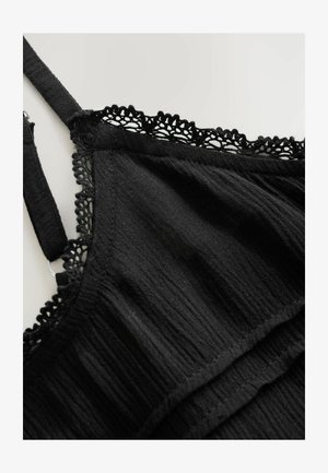 Zwarte mouwloze top van textuurstof, met een kanten rand langs de halslijn en zoom. Verstelbare schouderbanden en ruches als ontwerpdetails.