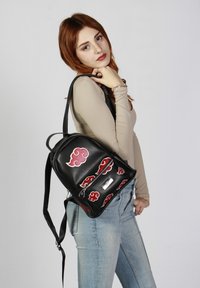 Sac à dos en cuir noir avec des motifs de nuages rouges. Comprend une poche zippée et des bretelles ajustables. Surface texturée avec des accents voyants.
