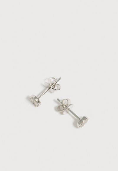 Paire de petites boucles d’oreilles en argent avec fermoir papillon, chacune présentant un groupe rond de pierres claires sur fond blanc.