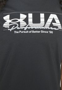 Svart t-shirt i bomull med en vit logotyp som har texten "UA" och "Performance" samt frasen "The Pursuit of Better Since '96."