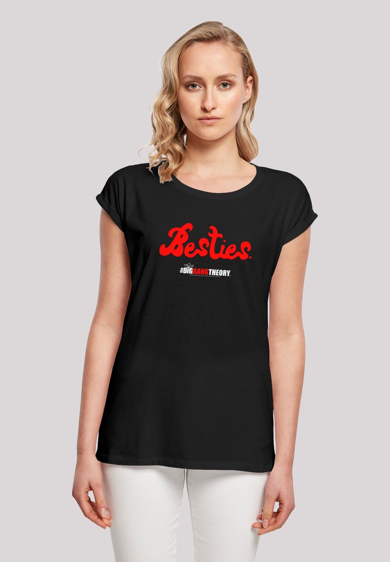 Juodas marškinėliai su sukritais rankovėmis, turintys raudoną užrašą "Besties" ir "Didžiojo sprogimo teorija" logotipą žemiau balta spalva, pagaminti iš minkštos medvilnės.