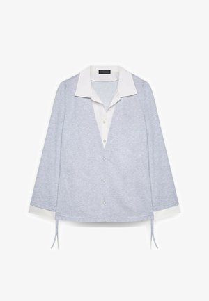 Top gris claro con cuello blanco, mangas largas, botones al frente y lazos decorativos en el dobladillo. Tela suave y texturizada.