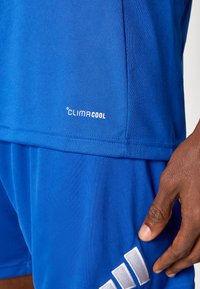 Αθλητική μπλούζα και σορτς ClimaCool σε ζωντανό μπλε ύφασμα, με αεριζόμενη υφή, λευκ ή σημεία και άνετη εφαρμογή.