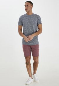 Siva melange majica kratkih rukava, u kombinaciji s bordo šortsu. Ima ležeran kroj i naglasak bijelih tenisica. Diskretni branding na rubu majice.