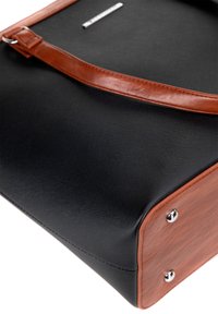 Sac structuré noir avec une surface texturée, accents en cuir marron, une bandoulière et des embellissements en métal argenté. Base notable en bois.