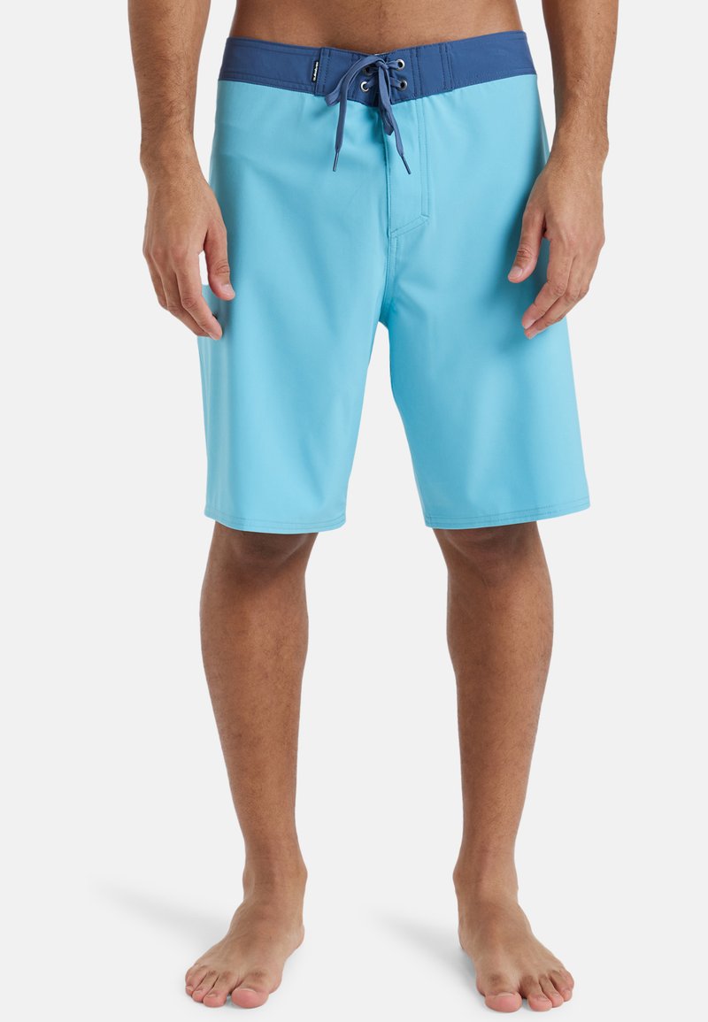 Shorts de bain bleu clair avec une taille bleu foncé, à lacets à l'avant et texture lisse. Se porte au-dessus du genou sans motifs visibles.