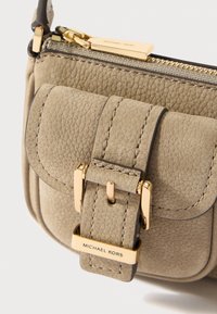 Bež kožna torba s preklopom koja se zatvara zlatnim kopčanjem, teksturiranom površinom i detaljem s brendom. Patentni zatvarač za sigurnu čvrstoću.