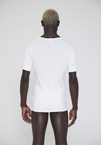 White cotton t-shirt with short sleeves, round neckline, and fitted design. Smooth texture, no visible patterns or accents.