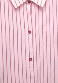 Chemise rose avec fines rayures verticales rouges et boutons rouges assortis, montrant les détails du col et de la patte de boutonnage.