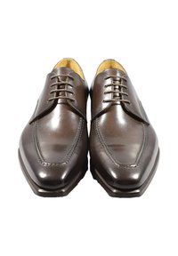 Scarpe in pelle marrone con finitura lucida, punta tonda, dettagli di cucitura in rilievo e chiusura con lacci a cinque occhielli. Suola piatta, design classico.