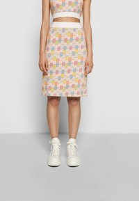 Kudotun kaksiosainen asuste, jossa on kuvioitu toppi ja tiukka hame. Sisältää pastellivärejä ruutukuviossa ja erottuvan valkoisen vyötärön.