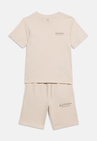 Σετ μπεζ κοντομάνικης μπλούζας και σορτς με λογότυπα «Jack & Jones Archive Selection» στο στήθος και στο αριστερό μηρό, απλωμένα επίπεδα.