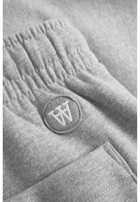 Pilki treninginiai šortai su tekstūruotu juosmens diržu, šonine kišenė ir apvaliu siuvinėtų logotipu su inicialais "WA" centre.