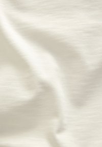 Hellcremefarbener Stoff mit weicher, glatter Textur und leichtem Glanz, der ein dezentes, gleichmäßiges Webmuster aufweist.