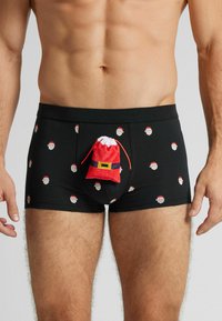 Czarne bokserki z powtarzającym się nadrukiem twarzy Świętego Mikołaja oraz trójwymiarową czerwoną i białą kieszenią w kształcie Mikołaja z przodu, wykonane z miękkiego, elastycznego materiału.