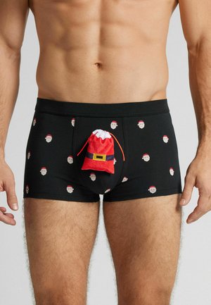 Svarte bokser-shorts med gjentatte trykk av julenissens ansikt og en 3D-rød og hvit julenissepose foran, laget av mykt og elastisk stoff.