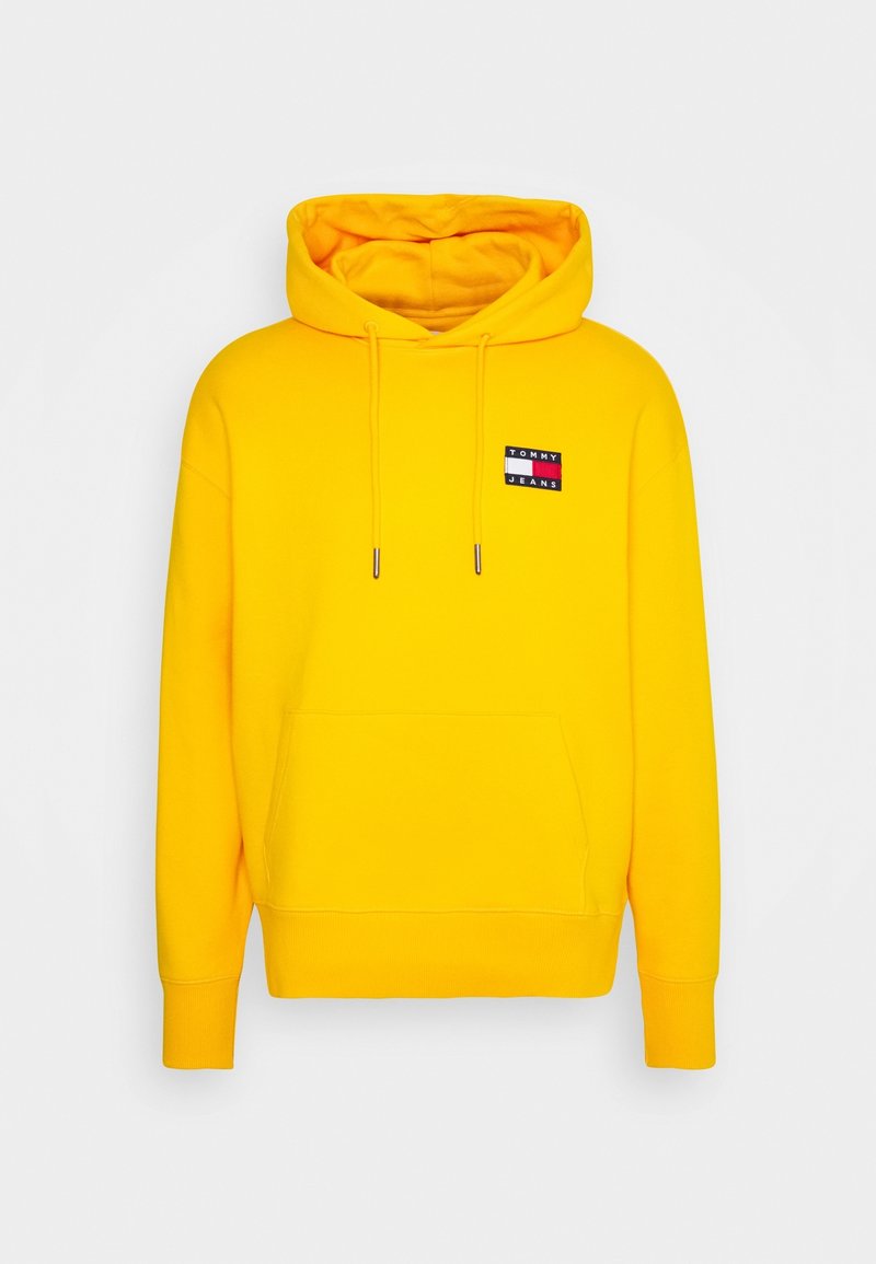 Sweat à capuche jaune vif avec poche avant et cordons, avec un petit logo rectangulaire "Tommy Jeans" sur la poitrine.