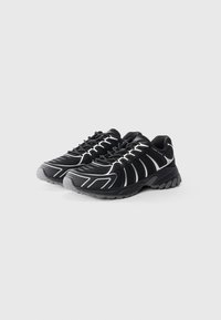 Scarpe sportive nere con tomaia in rete, dettagli bianchi e grigi, punta arrotondata e suola in gomma testurizzata. Presenta un design con lacci.