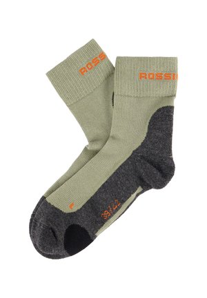 Para zielono-ciemnoszarych skarpetek trekkingowych z wzmocnionym piętą i palcami, pomarańczowym logo na mankiecie oraz oznaczeniami rozmiaru na podeszwie.