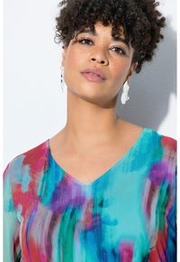 Blusa leggera dai motivi astratti e colorati in tonalità di turchese, rosa e viola con scollatura a V. Presenta una texture particolare e maniche lunghe.