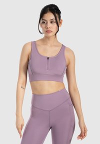 Top corto lila con cremallera frontal, textura suave y diseño de espalda nadadora, combinado con leggings de tiro alto a juego que presentan detalles en las costuras.