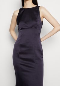 Ärmlös klänning i djupt marinblå satin med en figurnära silhuett, med rund halsringning och slät textur, designad för en elegant look.