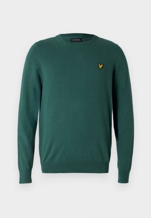 Žalias megztinis su apvalia iškirpte, ilgomis rankovėmis ir geltonu siuvinėtu logotipu kairėje krūtinės pusėje. Lygus audinys, aptemptas siluetas.