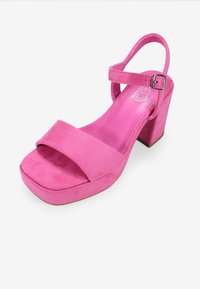 Sandalía de plataforma de ante rosa con tacón cuadrado, que cuenta con una amplia correa frontal y una correa ajustable en el tobillo con hebilla de metal. Forro interior suave.