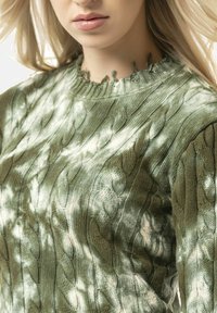 Strickpullover in Hellgr�ün, mit einem Zopfstrick-Muster und einem ausgefransten Kragen. Das weiche Material und die gerippten Ärmelbündchen unterstreichen die Designdetails.