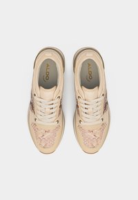 Baskets à imprimé serpent beige et rose avec des lacets blancs, vues de dessus, montrant le logo ALDO à l'intérieur de chaque chaussure.