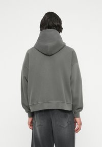 Harmaa huppari, jossa on lyhennetty muotoilu, ribbikujanteet ja pehmeä rakenne. Takakuvassa on vähäiset saumat eikä näkyviä logoja tai kuvioita.